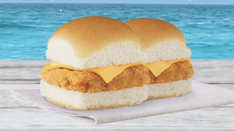 Two White Castle Panko Breaded Fish Sliders on white wood surface with blue water in background