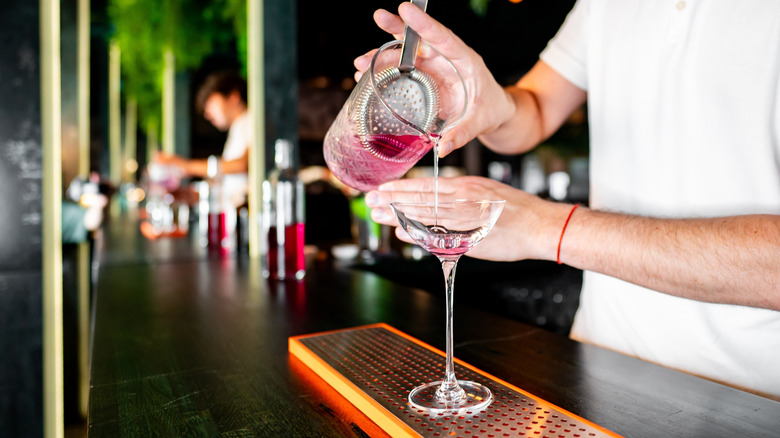 bartender pouring pink cocktail