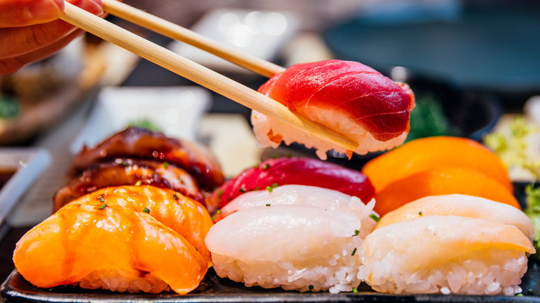 Person holding sushi with chopsticks