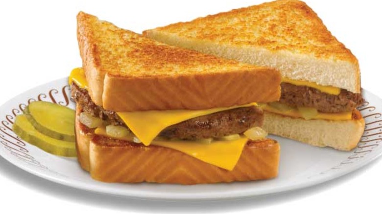 A patty melt between two thick slices of bead on a white plate.