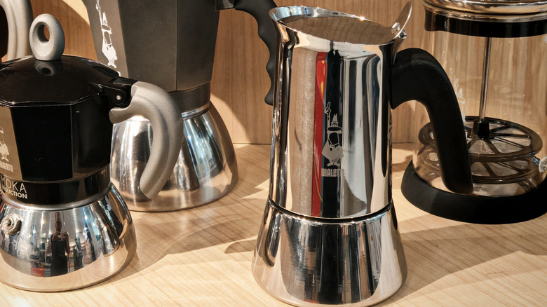 A stainless steel Bialetti New Venus next to other Bialetti models