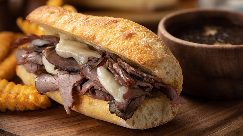 French dip sandwich with fries on wooden board