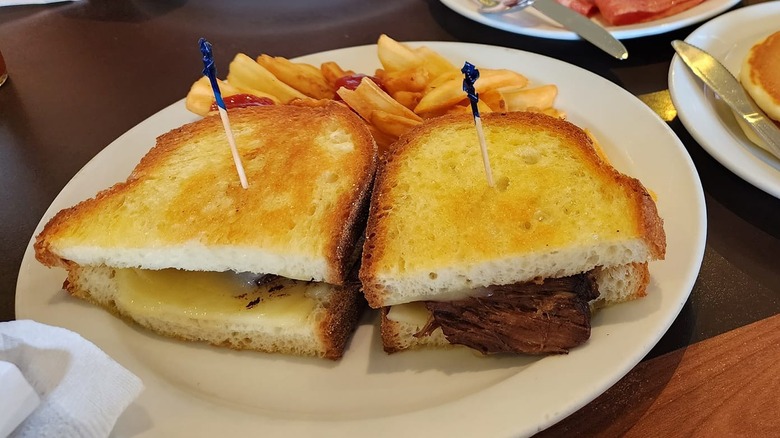 Denny's steak sandwich on white plate with fries