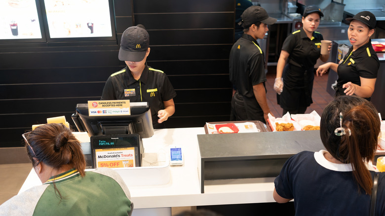 cashiers serving customers in busy McDonald's