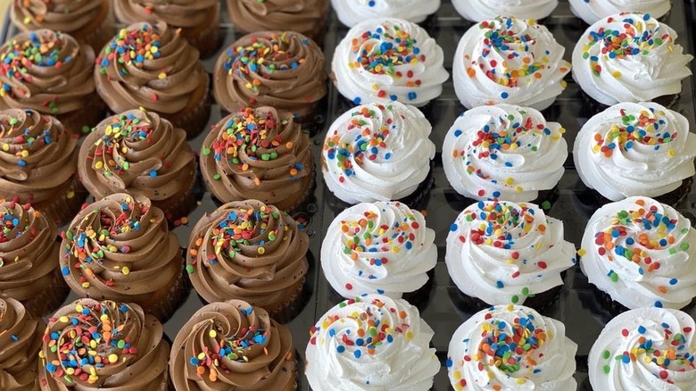 Tray filled equally with white and chocolate cupcakes topped with sprinkles