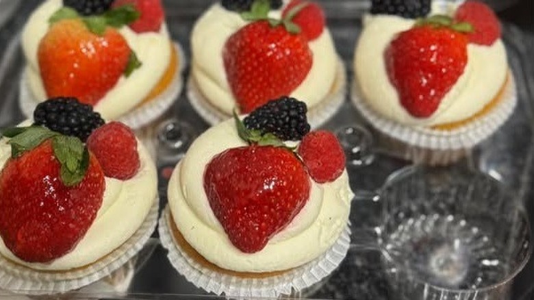 Cupcakes topped with Chantilly cream, strawberries, blackberries, and raspberries