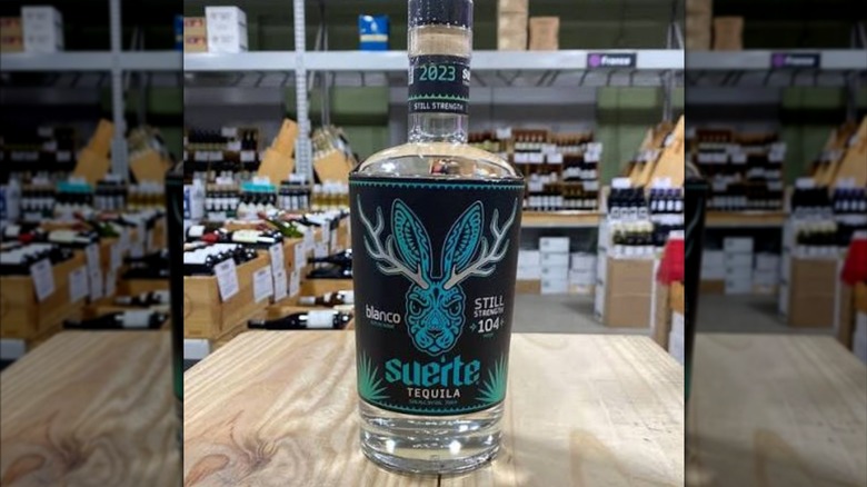 Unopened bottle of Suerte Still Strength tequila on a wooden table in a wine store