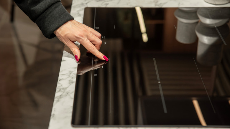 Touch-sensitive induction cooktop operated by woman's hand