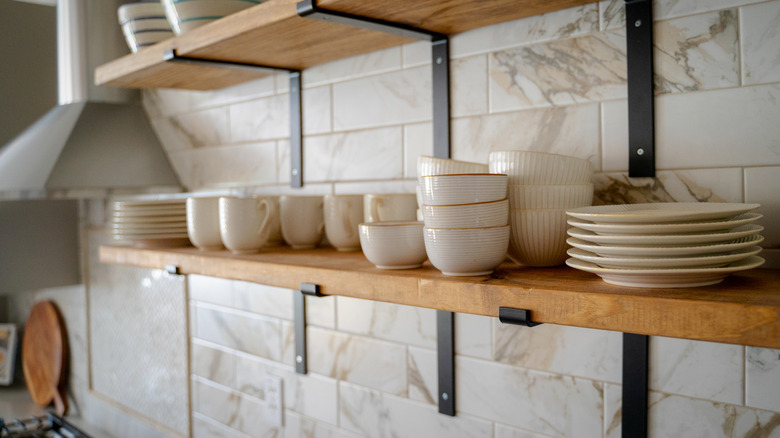 Close up of open kitchen shelves with cups and plates and exhaust hood