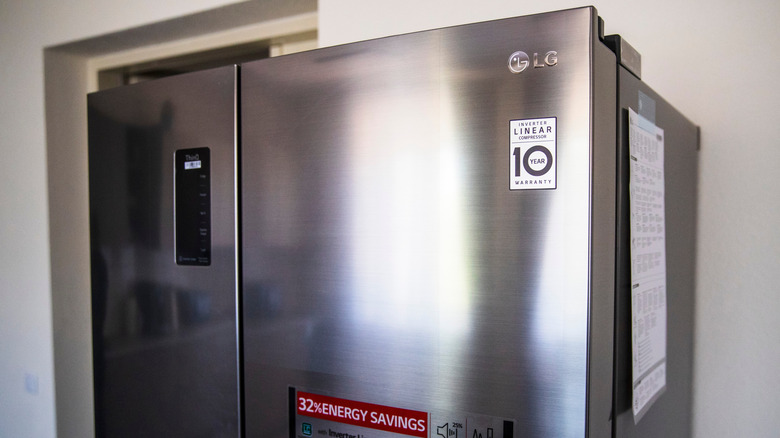 The top of a modern LG stainless steel refrigerator against wall