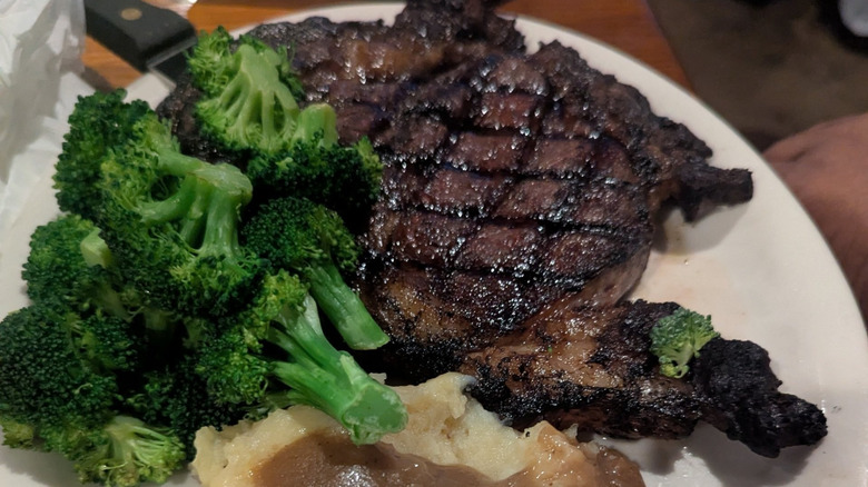 Large steak with broccoli on a white plate