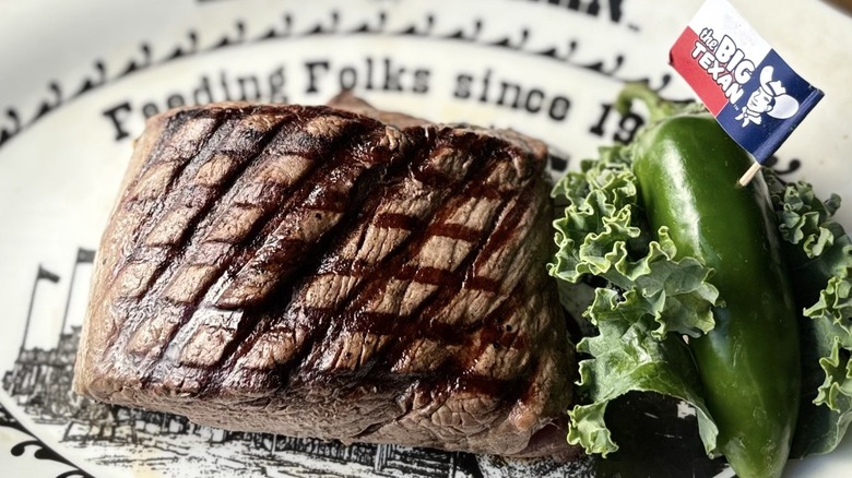 cut of steak on a plate and jalapeno garnish at The Big Texan