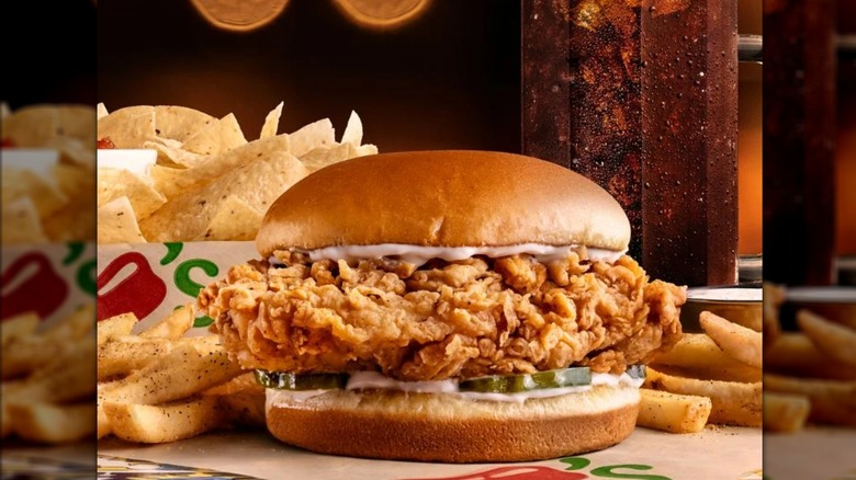 Chili's crispy chicken sandwich with mayo and pickles, with fries and tortilla chips in background