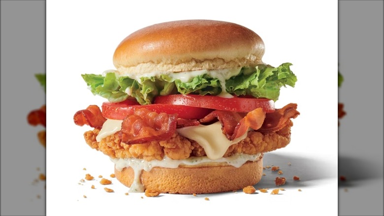 Crispy chicken sandwich with bacon, cheese, tomato, lettuce, and ranch sauce