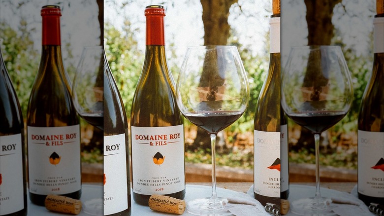 A bottle of Domaine Roy & Fils wine and a glass of red wine