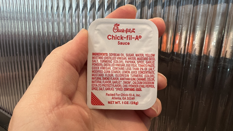 Hand holds a single-serving Chick-fil-A Sauce packet