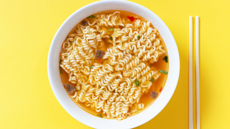 Instant noodle soup in a white bowl on a yellow background