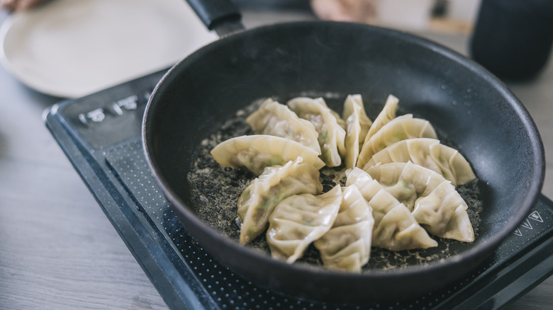 gyozas frying in a pan