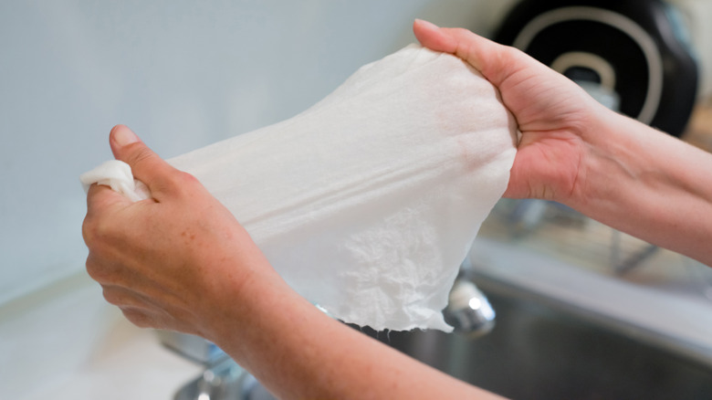 Close-up of hands stretching a wet paper towel over sink