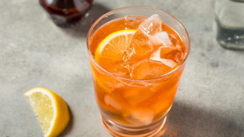 An orange spritz cocktail in a glass with ice and lemon