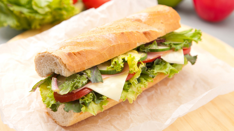 Homemade sub sandwich with fresh veggies on white parchment paper