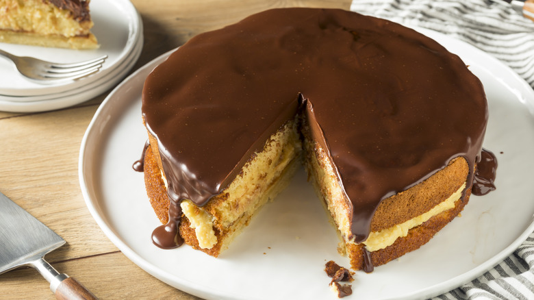 Boston cream pie with a slice taken out on white plate