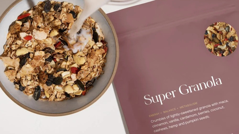 Overhead shot of milk being poured into bowl of Super Granola alongside bag