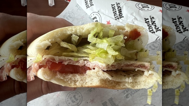 hand holding half-eaten Vito sandwich over Jimmy John's packaging, mirrored image