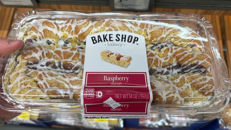 Hand holding packet of Bake Shop Raspberry Danish in front of Aldi shelf