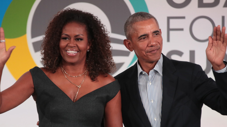 Michelle and Barack Obama smiling and waving