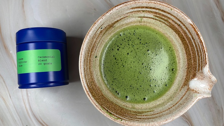 Matcha in beige chawan next to Rocky's Ceremonial Blend Matcha tin