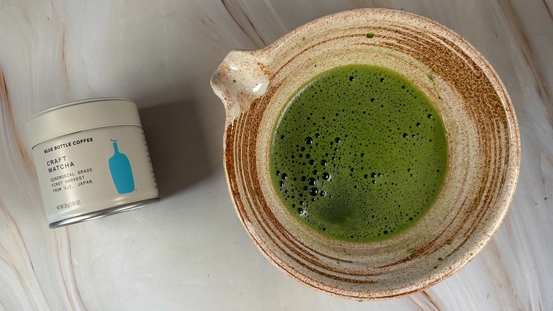 Matcha in beige chawan next to Blue Bottle Matcha tin
