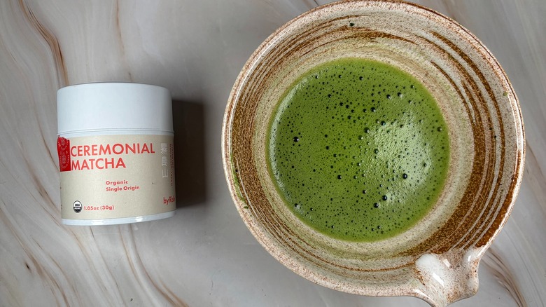 Matcha in beige chawan next to Rishi Ceremonial Matcha tin