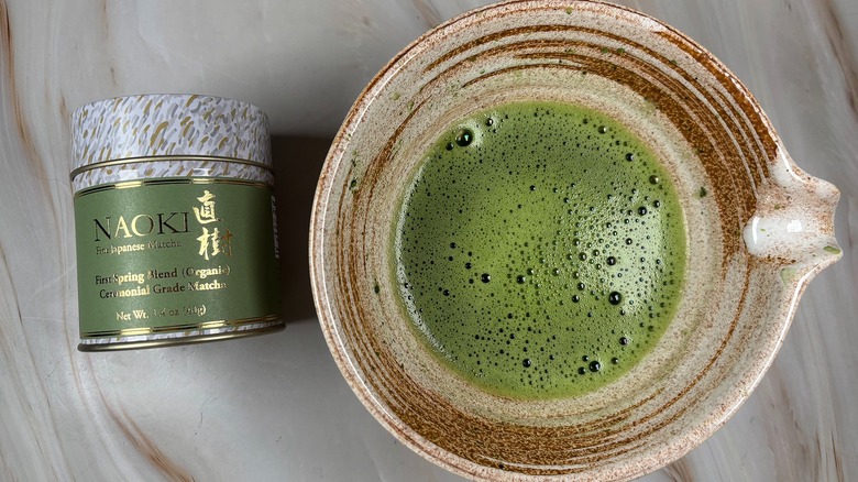 Matcha in beige chawan next to Naoki Matcha tin