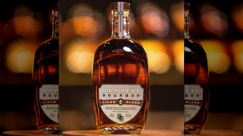A bottle of Barrell Bourbon Cigar Blend posed for the camera in front of blurred background lights