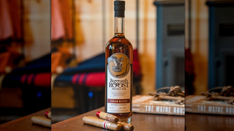 A bottle of Buzzard's Roost Double Oak Cigar Blend on a table with three cigars placed in front