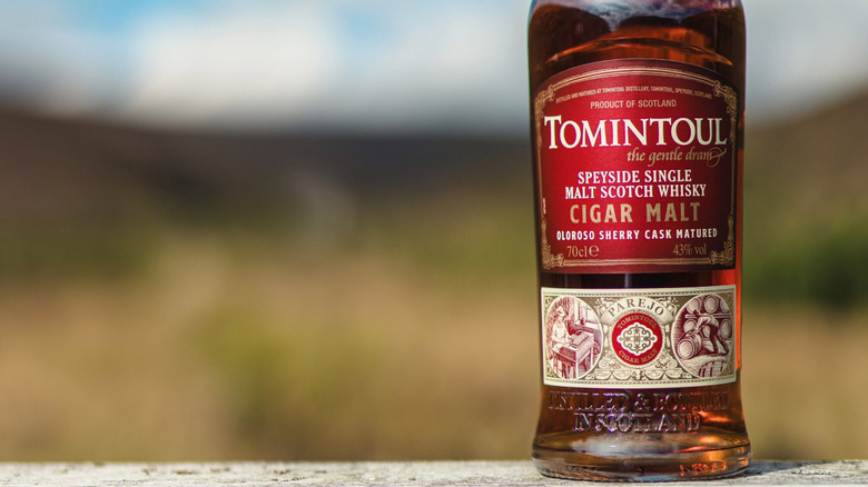 A close shot of a bottle of Tomintoul Cigar Malt with a blurred outdoors background
