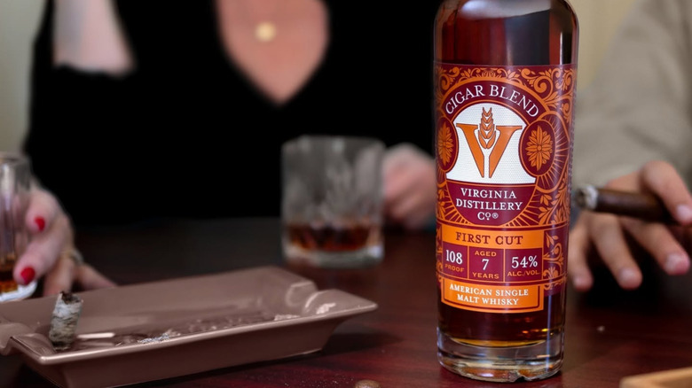 A bottle of Virginia Distillery Co. Cigar Blend on a table next to an ash try with people in the background
