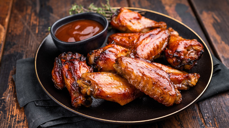 Sweet and sour wings on a plate with a sauce cup