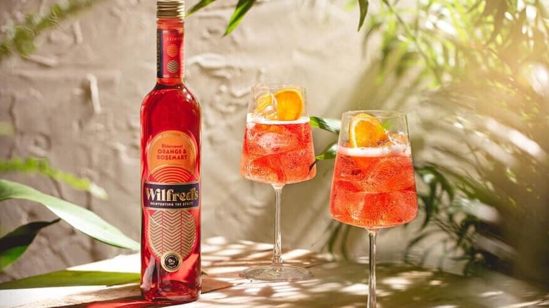 A bottle of Wilfred's alongside two spritzes with tropical plants.