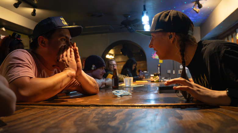 a person yelling an order across the bar to a bartender