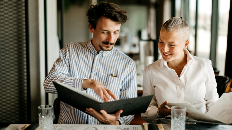 two people reading a menu at a restaurant