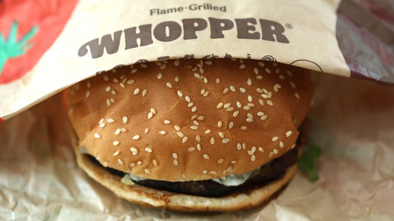 A Burger King Whopper halfway covered by its wrapper