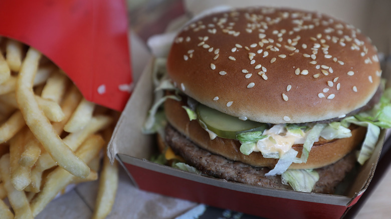 A Big Mac in its container sitting near some French fries