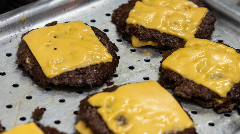 Fast food cheeseburger patties on metal surface