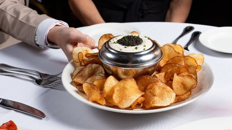 The Capital Grille waiter serving plate of chips with caviar