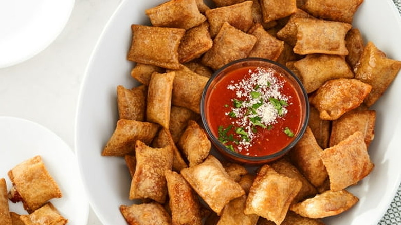 A platter of pizza snack rolls and marinara sauce
