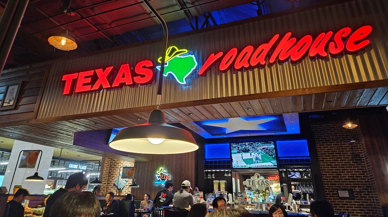 Interior of a busy Texas Roadhouse, with sign and customers