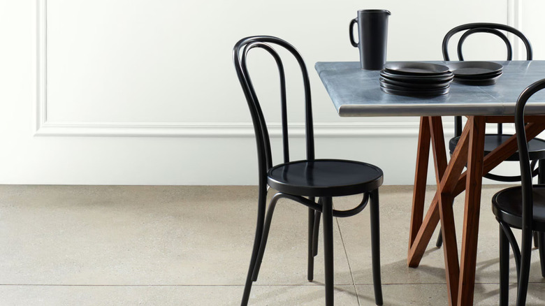 Silver table with black dishes and chairs against white wall