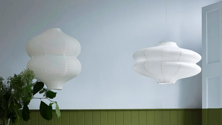 Two paper lanterns against a bluish white wall with dark green trim
